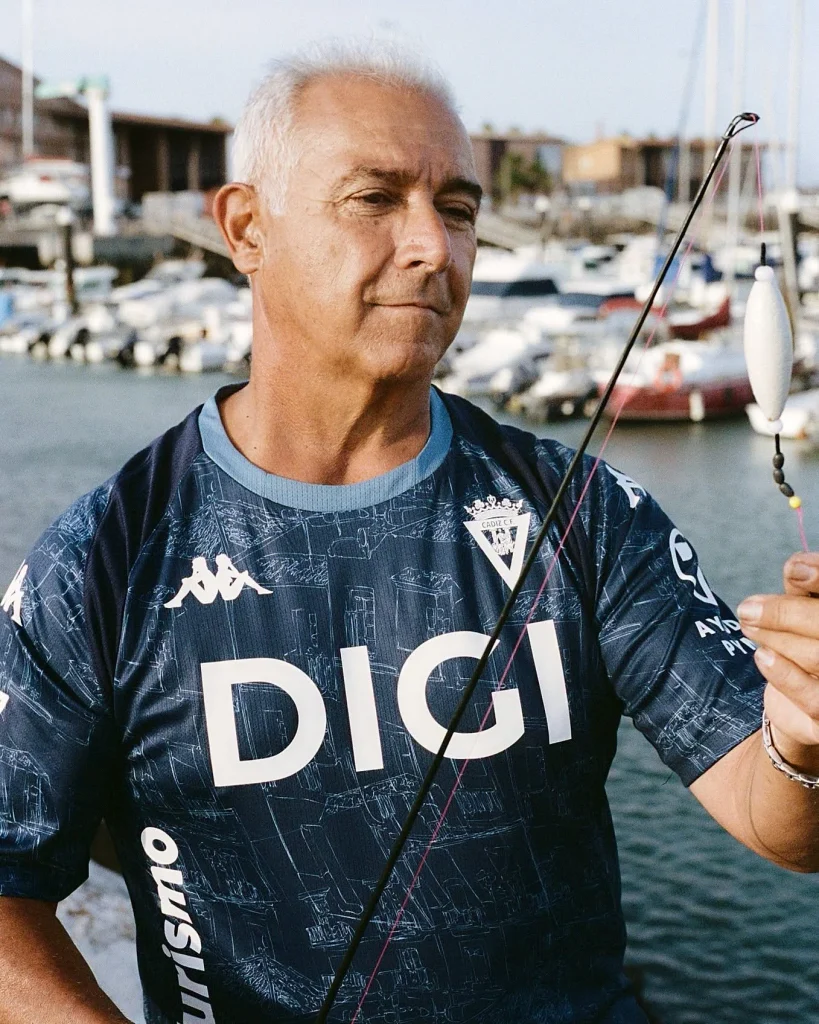 The Cádiz CF 2026/27 Away kit by Kappa, featuring a dark navy base with a detailed light blue sketch graphic of the city's streets and architecture.